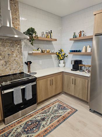 A kitchen with a stone backsplash and wooden cabinets.